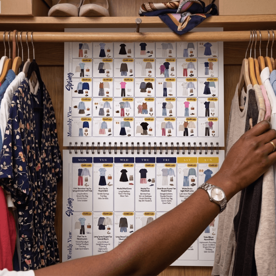 Woman reaching for the outfit calendar hanging on her closet rod, open to spring capsule wardrobe outfit pages